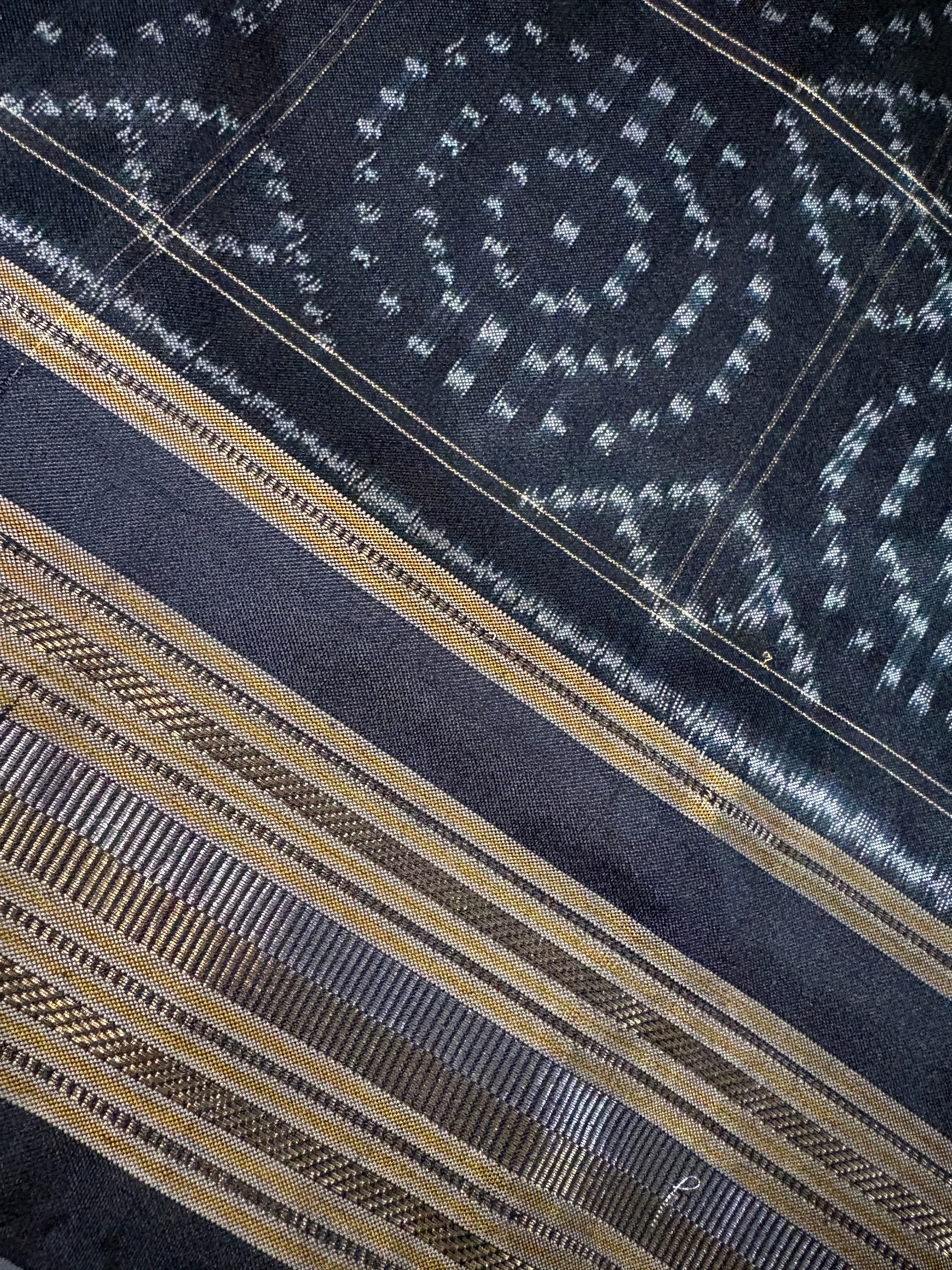 Close-up of a black and gold handwoven silk saree border showcasing intricate weave detail.